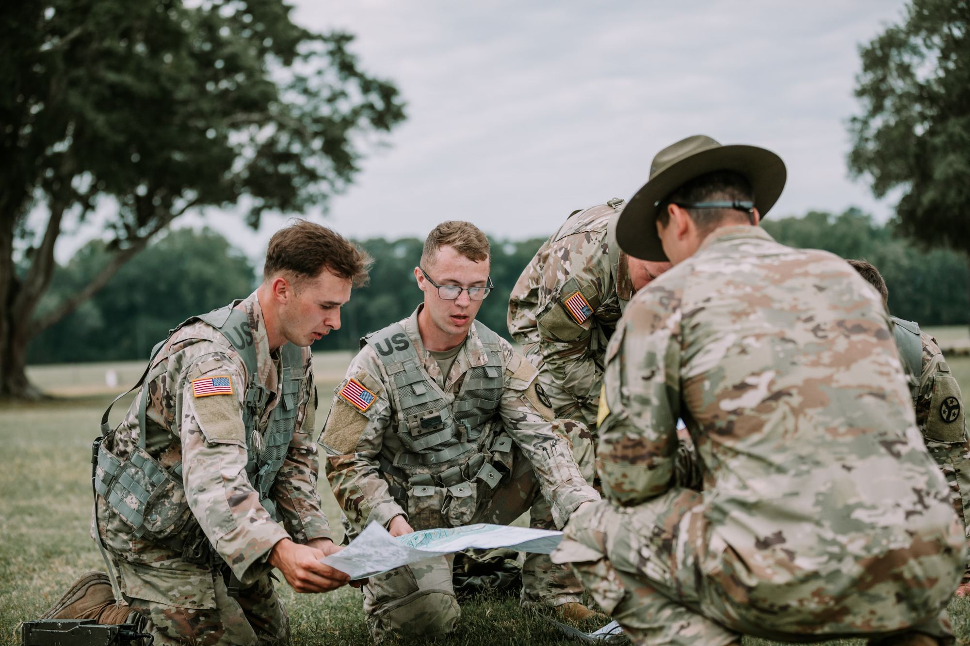 Soldiers kneeling in a field around a paper map